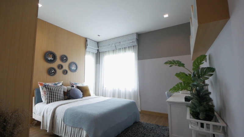 Mala spavaća soba sa policama na zidu, svetlim zavesama i jednostavnim dekorom